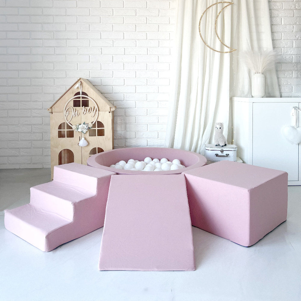 Roze speelset met een ballenbad met witte ballen, trapje links, helling in het midden en blok rechts.