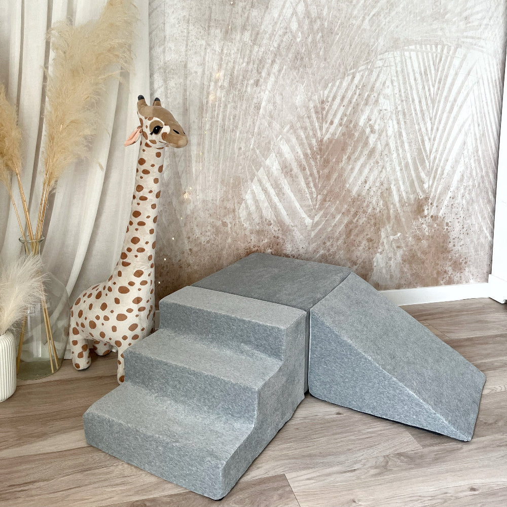 Grijs Soft Velvet speelparcours met trapje vooraan, rechthoekig blok en helling rechts, naast een pluchen giraf.