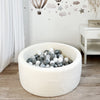 Rond wit teddy ballenbad met witte en grijze ballen op een houtkleurige vloer in een kinderkamer.