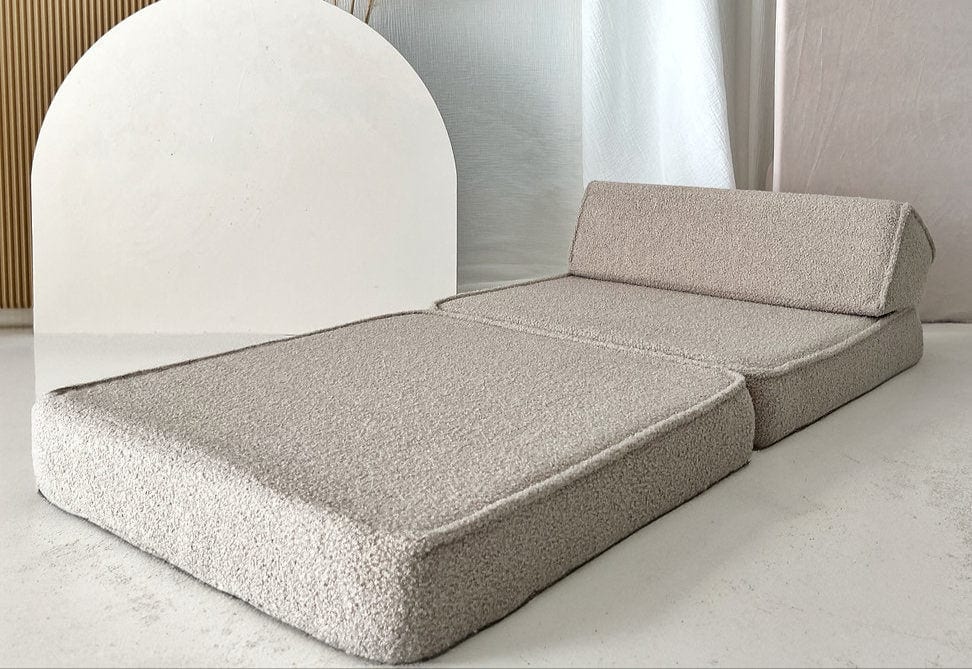 Beige bouclé lounger uitgeklapt als ligplek met een schuin rugkussen.