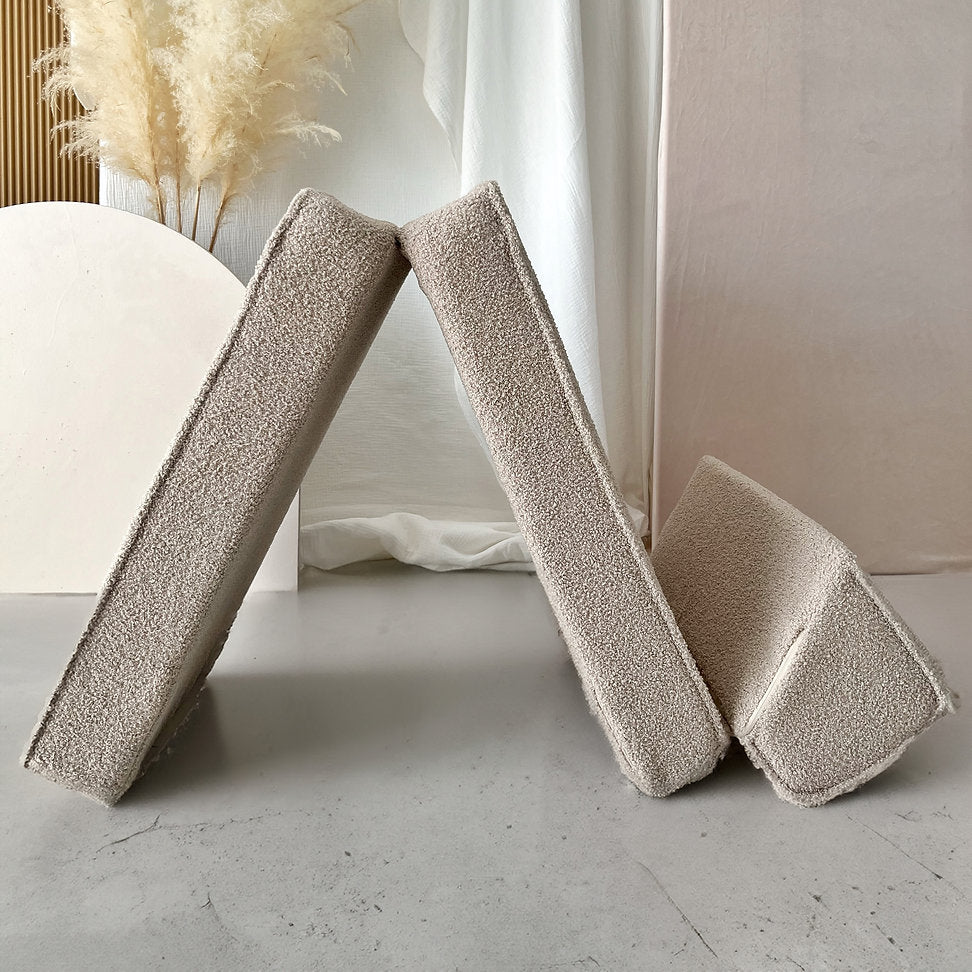 Beige bouclé lounger met de verbonden segmenten rechtop in een driehoekige speelopstelling.