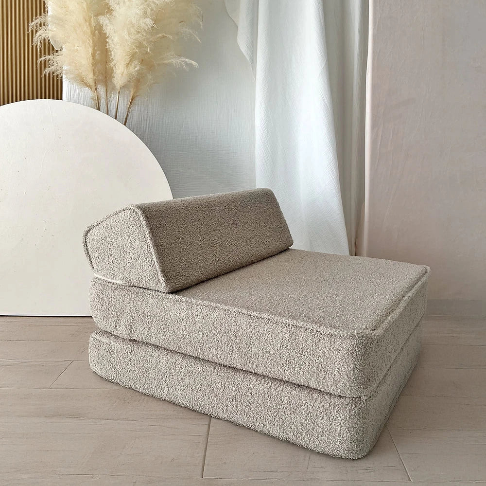 Beige bouclé lounger opgevouwen tot kinderstoel met twee gestapelde zitdelen en een schuin rugkussen.