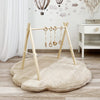 Beige wolkvormige teddy speelmat Cloud onder een houten babygym in een kinderkamer.