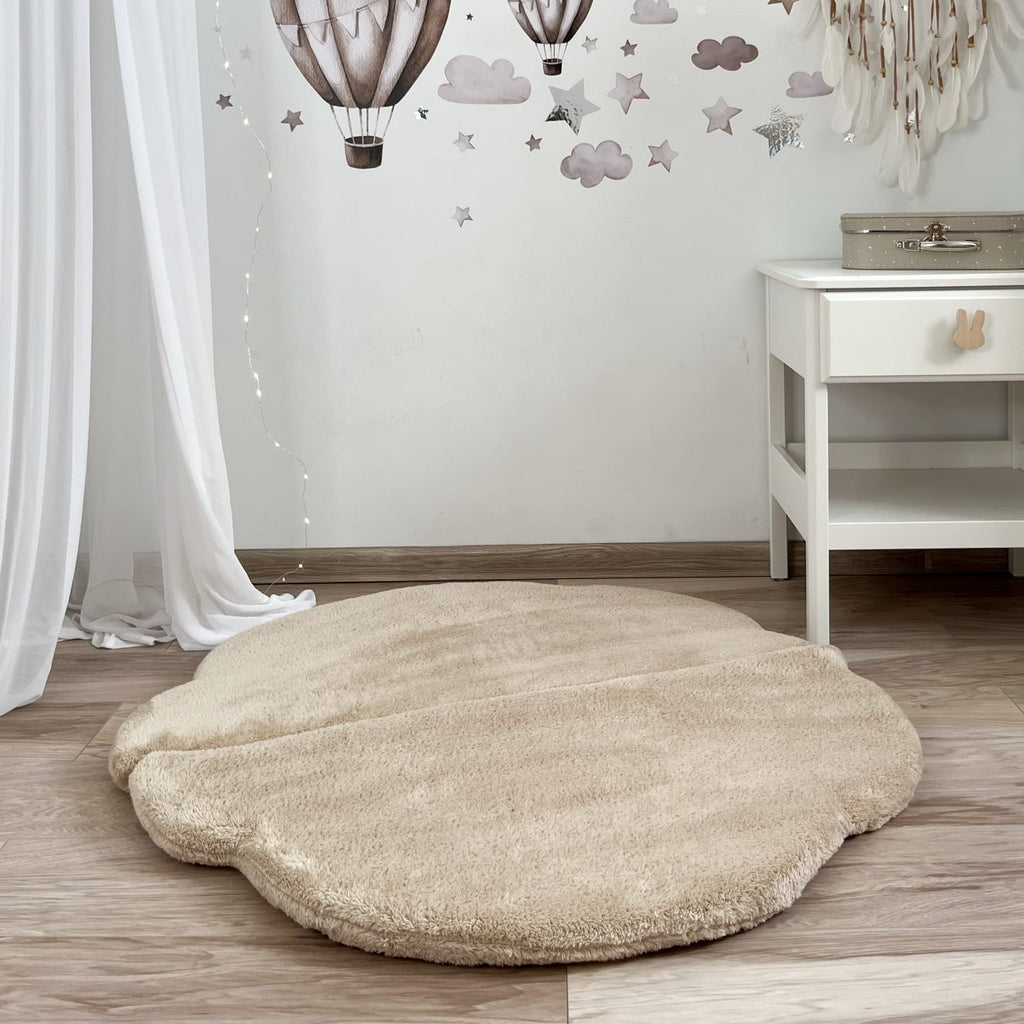 Beige wolkvormige teddy speelmat Cloud plat op de houten vloer in een kinderkamer.