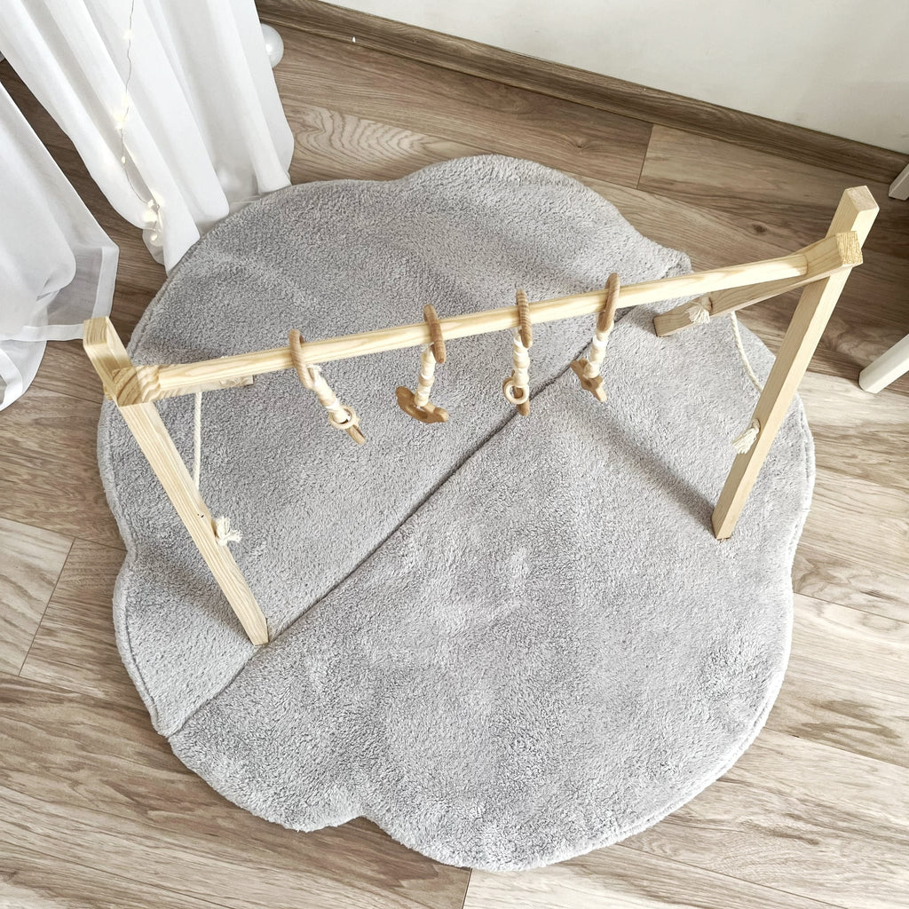Grijze teddy speelmat Cloud onder een houten babygym met hangspeeltjes, van bovenaf gezien.