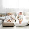 Twee kinderen liggen naast elkaar op een beige en een crèmekleurige bouclé zitzak.