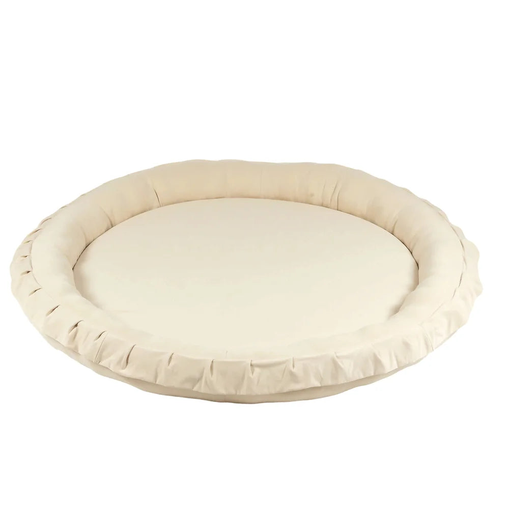 Rond lichtbeige katoenen speelnest met een opstaande, gewatteerde rand op een witte achtergrond.